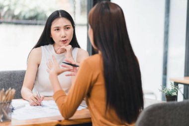 İki genç Asyalı iş kadını, ofiste planlama ve mali istatistikleri, yatırım piyasasını analiz etmek üzere yeni bir girişim projesini tartışıyor.