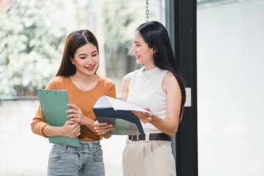 İki genç Asyalı iş kadını mali yönetim planlarını tartışıyor ve ofisteki yeni başlangıç projesi fikirlerini, mali planlamayı, istatistikleri ve yatırım piyasasını analiz ediyorlar.