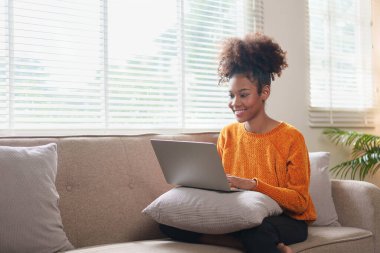 Dizüstü bilgisayar kullanan mutlu genç bir kadın Webinar seyrediyor, çevrimiçi çalışıyor, bilgisayar ekranı öğreniyor web dersleri alıyor ya da evden uzaktan kumandalı sanal arama görüşmesi yapıyor..