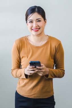 Dost canlısı gülümseyen kendine güvenen Asyalı kadın beyaz arka planda el ele tutuşmuş akıllı telefonu tutuyor.