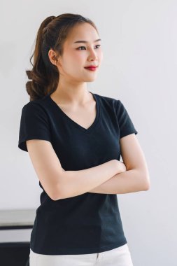 Dost canlısı gülümseyen kendinden emin Asyalı kadın beyaz arka planda kollarını kavuşturmuş duruyor.