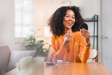 Kıvırcık saçlı güzel bir kadın evde makyaj yapıyor..