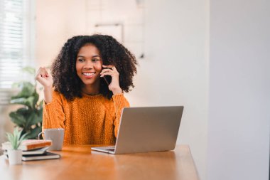 Gülümseyen Afrikalı Amerikalı Kadın Evde çalışırken telefonda konuşuyor
