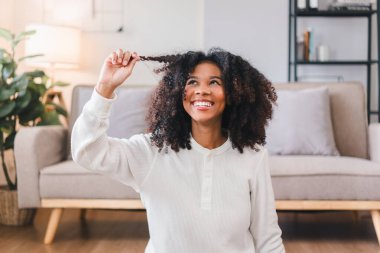 Gülümseyen Afro-Amerikan Kadın Kıvırcık saçlarını içeride kabartıyor.
