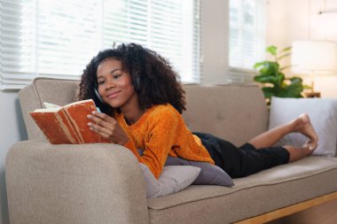 Evde Kitap okurken Afro-Amerikalı Kadın Kanepede dinleniyor