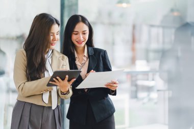 Modern ofiste iş ekibi tabletle tartışıyor.