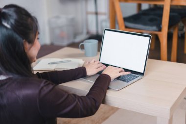 Boş ekranlı dizüstü bilgisayarda çalışan bir kadın.