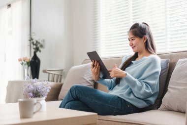 Gülümseyen Asyalı Kadın Evde Tablet Kullanırken Koltukta Rahatlıyor