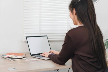 Ev ofisinde boş ekranlı laptop kullanan bir kadın.