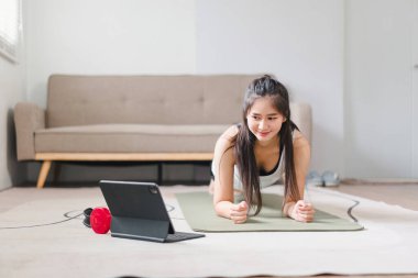 Asyalı genç bir kadın evde tahta egzersizi yapıyor. spor, fitness ve sağlıklı yaşam tarzı konsepti