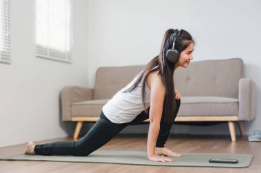 Evde egzersiz yapan genç bir Asyalı kadın profesyonel spor eğitmeninin talimatlarını tekrarlıyor..