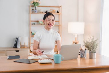 Ofis masasında çalışan gülümseyen kadın.