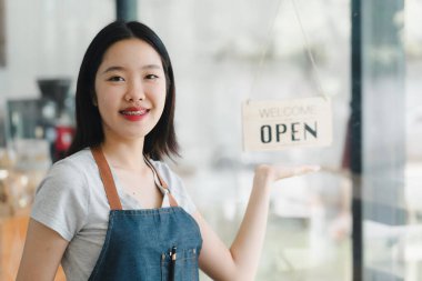 Kahvede açık tabela tutan gülümseyen kadın, müşterileri karşılıyor..