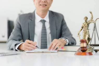 Takım elbiseli bir profesyonel masada yasal sembollerle notlar yazar..