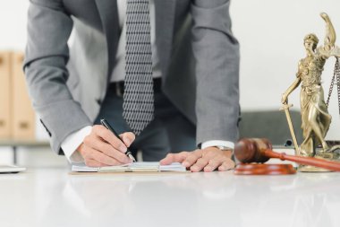 Takım elbiseli bir profesyonel masada yasal sembollerle notlar yazar..