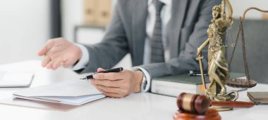 Hukukçu, yakınlardaki adalet terazisi ve tokmak ile belgeleri tartışıyor..