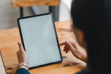 Tahta masa üzerinde tablet kullanan bir kişi, teknoloji ve etkileşim sergiliyor.