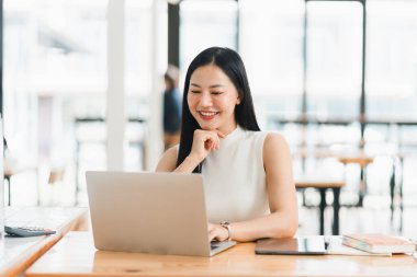 Günümüz iş yerinde dizüstü bilgisayarda çalışırken gülümseyen bir kadın..