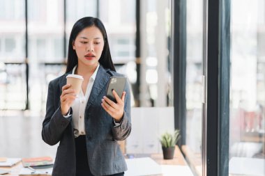 Modern ofiste telefona kahve ile bakan profesyonel bir kadın.