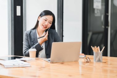 Verimli bir iş kadını, modern ofiste dizüstü bilgisayarla çalışıyor.