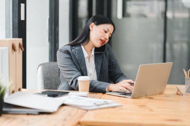 Modern ofis masasında birden fazla işi olan meşgul profesyonel bir kadın.
