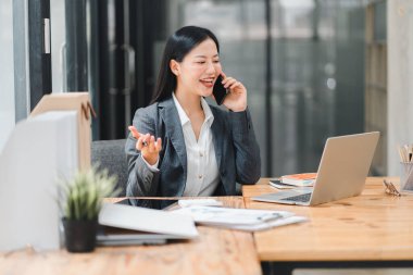 Telefonda etkili bir iş kadını, sohbete dalmış ve gülümsüyor.