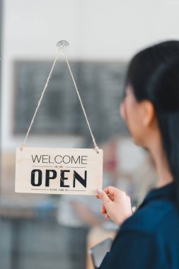 Kadın tarafından gösterilen açık tabela, müşterileri içeri davet ediyor..