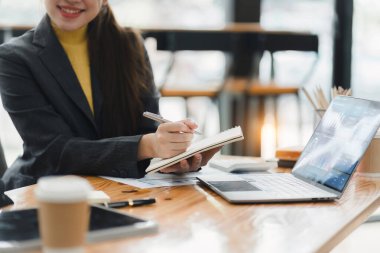 Haritalar ve dizüstü bilgisayarla finansal analiz üzerinde çalışan iki kadın.