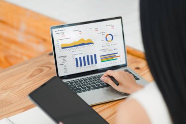 İş kadını, çeşitli performans ölçümleri ve analizleri gösteren dijital bir satış paneliyle etkileşime girer