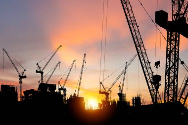 İnşaat alanının siluetleri ve günbatımı arkaplanlı inşaat vinçleri