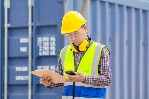 Engineer with clipboard checklist in industry containers cargo, Foreman dock worker in hardhat and safety vest control loading containers box from cargo