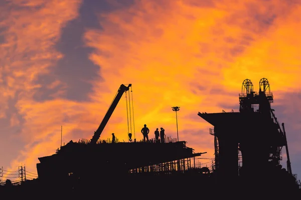 エンジニアと労働者のシルエット建設現場の背景 夕方の日没時の建設現場 — ストック写真