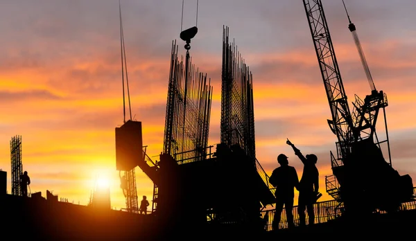エンジニアと労働者のシルエット建設現場の背景 夕方の日没時の建設現場 — ストック写真