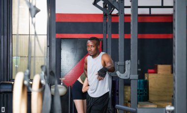 Genç adam spor salonunda güçlü duruyor ve kaslarını esnetiyor, spor ve spor kavramları.