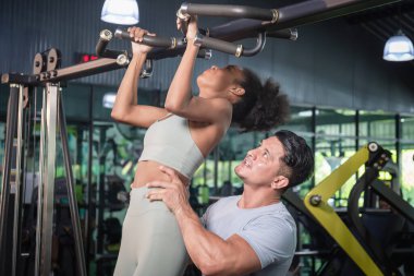 Antrenör ve genç sporcu, kişisel eğitmen spor, spor ve spor konseptlerinde kaslarını esneten genç kadına yardım ediyor.