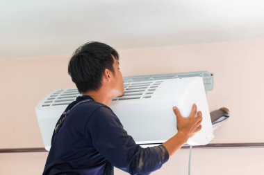 Elektrikçi havalandırma ünitesi kuruyor, teknisyen müşterinin evine klima kuruyor, tamirci havalandırma ünitesini tamir ediyor, onarım ve onarım işleriyle uğraşıyor.