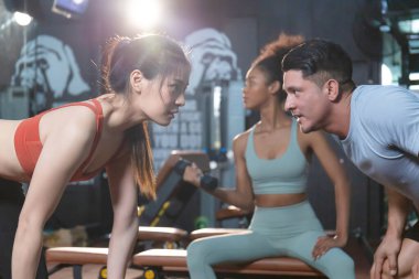 Antrenör ve genç sporcu, kişisel eğitmen spor, spor ve spor konseptlerinde kaslarını esneten genç kadına yardım ediyor.