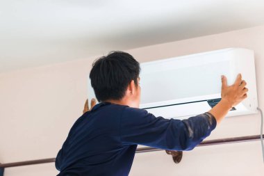 Elektrikçi havalandırma ünitesi kuruyor, teknisyen müşterinin evine klima kuruyor, tamirci havalandırma ünitesini tamir ediyor, onarım ve onarım işleriyle uğraşıyor.