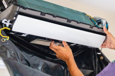 Teknisyen içeride klimayı temizliyor, modern klimayı tamir ediyor, bakım ve tamir kavramlarını tamir ediyor.