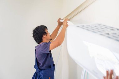 Elektrikçi havalandırma ünitesi kuruyor, teknisyen müşterinin evine klima kuruyor, tamirci havalandırma ünitesini tamir ediyor, onarım ve onarım işleriyle uğraşıyor.