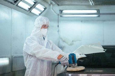 Tamirci, öğütme aletleriyle çalışır. Araba parçalarının zımparalanması. Garaj boyama servisi onarımı ve bakım işleri