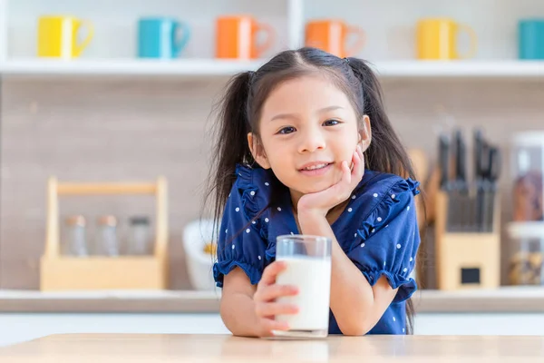 stock image Cute little girl with glass of milk at table in kitchen, Happy child girl drinks milk