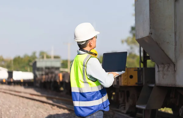 Engineer under inspection and checking construction process railway locomotive repair plant, Engineer man in waistcoats and hardhats and with laptop in a railway depot