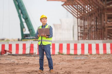 Altyapı şantiyesinde dizüstü bilgisayarı olan mühendis inşaat alanında çalışan işçi, inşaat alanındaki projeyi kontrol eden ustabaşı.