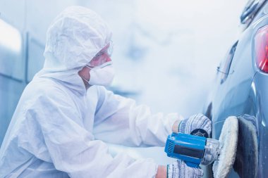 Tamirciye yakın çekim, öğütücü aletle çalışıyor. Araba parçalarının zımparalanması. Garaj boyama servisi onarımı ve bakımı