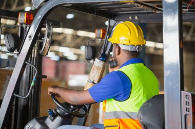 Depoda çalışan forklift yükleyicisi konteynır kutusunda çalışır. Depoda forklift kullanan işçi.