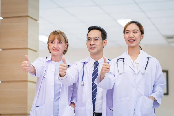 Team of medical doctors smiling while standing in the hospital, Doctors standing as a team showing thumbs up