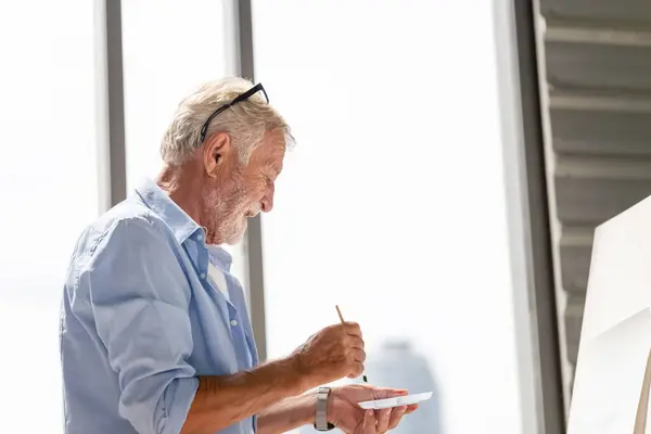 Senior man painting on canvas at home, Elderly man painting on a canvas, Happy retirement concepts