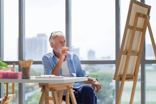 Elderly man painting on a canvas, Senior man painting on canvas at home, Happy retirement concepts