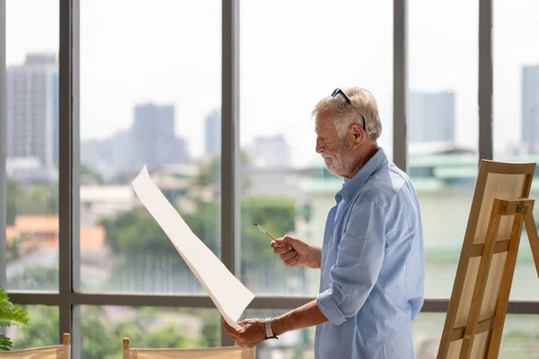 Senior man holding painting, Elderly man male artist drawing at art studio, Happy retirement concepts